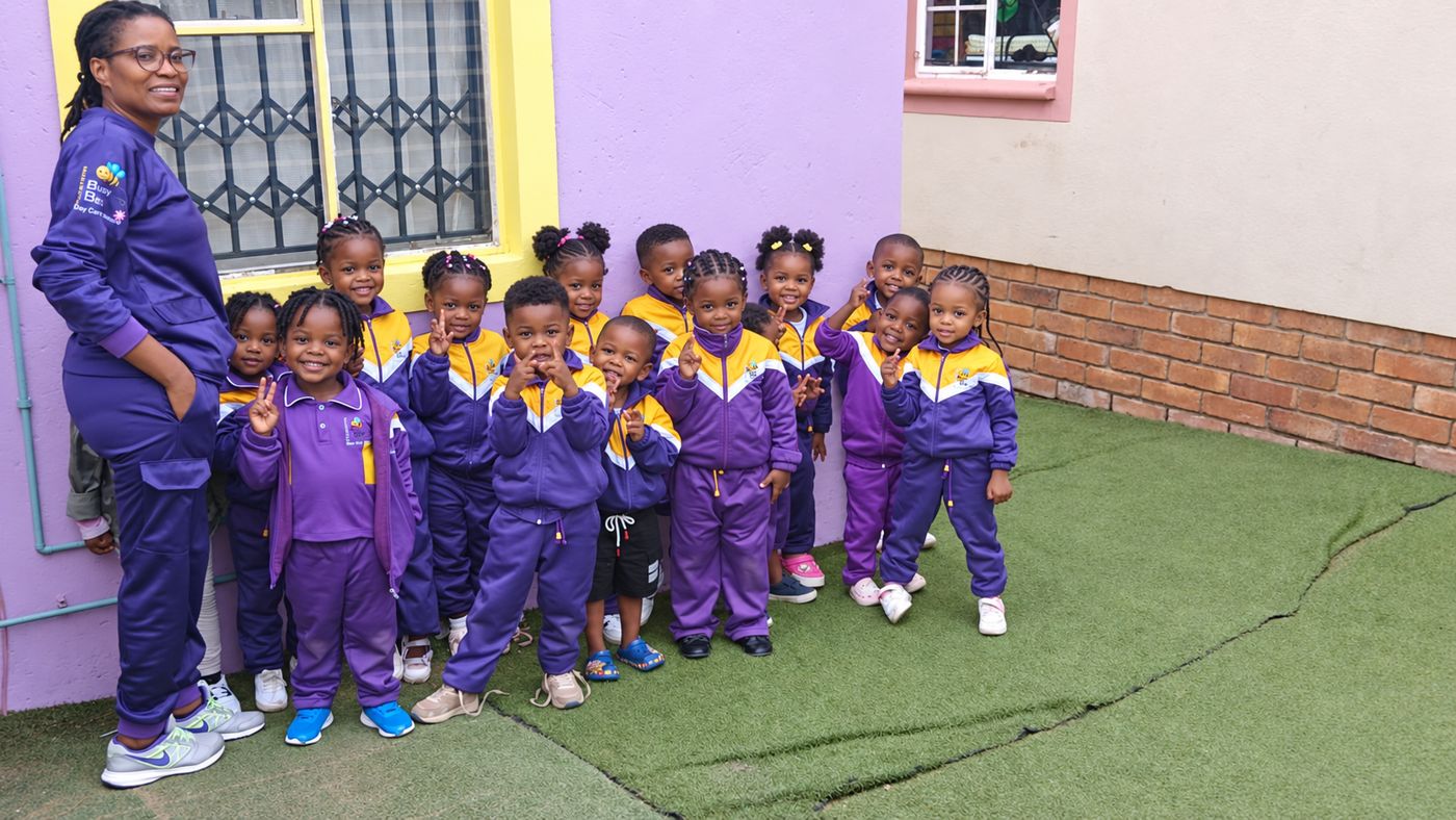 Children in purple and gold Busy Bee tracksuits with their teacher